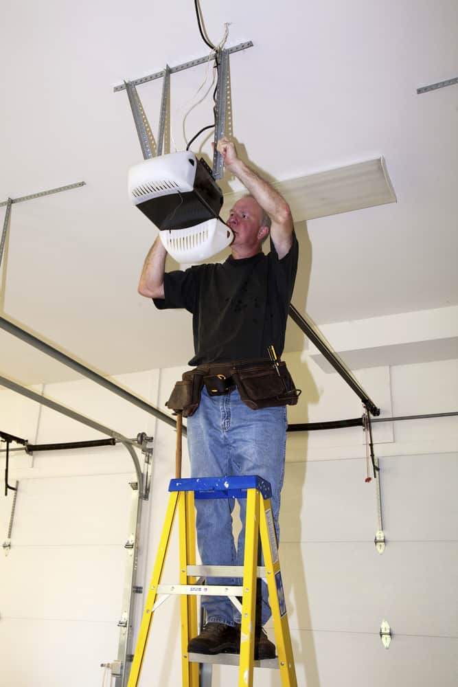 Man working on garage door opener on a ladder